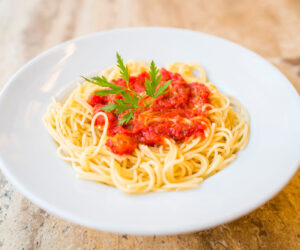 Delicious spaghetti pasta with tomato sauce and parsley, homemade healthy italian pasta on marble background, taste spaghetti