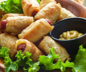 Crispy pigs in a blanket cocktail hotdogs wrapped in croissant dough served with spicy mustard