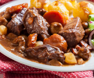 Beef Bourguignon stew served with baked potatoes on a plate. French cuisine