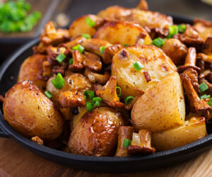 Baked potatoes with garlic, herbs and fried chanterelles in a cast iron skillet.