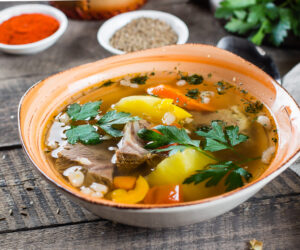 Asian soup shurpa with meat and vegetables in plate on wooned table. CLose-up