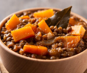 Lentil stew ragout with pumpkin and carrot in bowl on wooden table