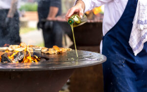 Roasting meat on a round barbecue with an open fire. The cook po